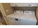 A bright laundry area featuring a white Whirlpool washer and dryer with white cabinets above for storage at 5640 E Bell Rd # 1047, Scottsdale, AZ 85254