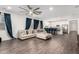 Spacious living room with hardwood floors, a ceiling fan, comfortable seating, and access to the modern kitchen at 5897 N 195Th Dr, Litchfield Park, AZ 85340