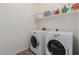 Functional laundry room with white washer and dryer and a shelf at 7050 S Fawn Ave, Gilbert, AZ 85298