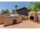 Outdoor kitchen features a stucco grill, a pizza oven, and a blue outbuilding in a beautiful backyard at 846 N 81St St, Mesa, AZ 85207