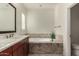 Bright bathroom featuring single sink, wood cabinets, tile floor, soaking tub, and plantation shutters at 919 W Yellowstone Way, Chandler, AZ 85248