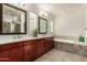 Bright bathroom featuring double sinks, wood cabinets, tile floor, soaking tub, and plantation shutters at 919 W Yellowstone Way, Chandler, AZ 85248