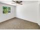 Bright bedroom with plush carpet, a ceiling fan and a large window offering views of the yard at 920 E Garnet Ave, Mesa, AZ 85204