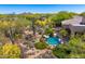 Backyard swimming pool with natural rock waterfall, surrounded by lush landscaping and a desert landscape at 9534 E Monument Dr, Scottsdale, AZ 85262