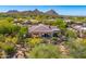 Scenic aerial view of a desert home nestled among lush trees and native vegetation, with mountains in the background at 9534 E Monument Dr, Scottsdale, AZ 85262