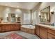 Bright bathroom with a soaking tub, separate vanities and plantation shutters at 9534 E Monument Dr, Scottsdale, AZ 85262