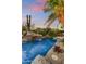 Swimming pool with waterfall feature and desert landscaping at twilight at 9534 E Monument Dr, Scottsdale, AZ 85262