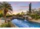 Luxurious pool with rock waterfall and desert views at twilight at 9534 E Monument Dr, Scottsdale, AZ 85262