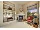 Cozy sitting area with fireplace, built-in shelves and a view of the lush landscape at 9534 E Monument Dr, Scottsdale, AZ 85262