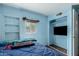Blue bedroom features built-in shelves, a window, and a closet with a TV at 1029 E Mckinley St, Phoenix, AZ 85006