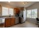 Well-lit kitchen with stainless steel refrigerator and appliances, complemented by wood cabinetry and tile floors at 10346 E Desert Dawn Dr, Gold Canyon, AZ 85118