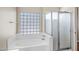 Primary bathroom with a glass block window, bathtub, and a glass-enclosed shower at 12441 W Windsor Blvd, Litchfield Park, AZ 85340