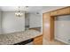 Kitchen island with granite countertop, dishwasher, wood cabinets, and tile flooring with adjacent living room at 12441 W Windsor Blvd, Litchfield Park, AZ 85340