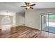 Bright living room featuring wood floors, a modern ceiling fan, and sliding glass doors to the backyard at 12441 W Windsor Blvd, Litchfield Park, AZ 85340