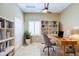 Bright home office featuring custom built-in bookshelves, a desk, stone floors, and a ceiling fan at 1470 W Bartlett Way, Chandler, AZ 85248