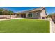 Wide shot of the backyard highlighting the expansive lawn, covered patio, and mature landscaping at 16785 W Montana De Oro Dr, Surprise, AZ 85387