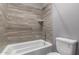 Bathroom shower and tub with neutral tone wall tile and matching fixtures at 16785 W Montana De Oro Dr, Surprise, AZ 85387