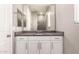Bathroom vanity with granite countertop, ample cabinet storage, and a large mirror reflecting a walk-in shower at 16785 W Montana De Oro Dr, Surprise, AZ 85387