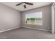 Cozy bedroom with neutral color palette, plush carpet, ceiling fan, and large window with blinds at 16785 W Montana De Oro Dr, Surprise, AZ 85387
