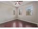 Bedroom featuring hardwood floors, three windows, and a ceiling fan at 19022 W Shangri La Rd, Surprise, AZ 85388