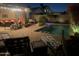 Inviting backyard oasis with sparkling pool, comfortable seating, and lush landscaping under the night sky at 2110 E Williams Dr, Phoenix, AZ 85024