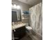 Neutral toned bathroom with a granite countertop, decorative shelves, and a patterned shower curtain at 2110 E Williams Dr, Phoenix, AZ 85024
