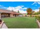 Expansive backyard with lush green lawn, covered patio, and well-maintained landscaping under a sunny sky at 5861 E Anderson Dr, Scottsdale, AZ 85254