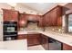 A kitchen showcasing dark wood cabinetry, a mosaic backsplash, and stainless steel appliances at 5861 E Anderson Dr, Scottsdale, AZ 85254