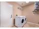 Laundry room features new white washer and dryer units near a large door and shelving at 5861 E Anderson Dr, Scottsdale, AZ 85254