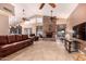 A spacious living room featuring a stone fireplace, leather furniture, tile flooring, and ceiling fans at 5861 E Anderson Dr, Scottsdale, AZ 85254