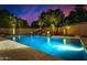 Inviting backyard pool with rock waterfall feature and lush landscaping under a vibrant sunset sky at 5861 E Anderson Dr, Scottsdale, AZ 85254