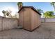 Backyard shed nestled against a privacy wall with a small table nearby amid gravel groundcover at 6424 E Aire Libre Ln, Scottsdale, AZ 85254