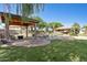 Large backyard with a manicured lawn, mature landscaping, a covered gazebo, and a rock waterfall pool at 6428 W Eugie Ave, Glendale, AZ 85304