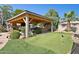 Backyard paradise with a putting green, outdoor kitchen, covered patio, and lush landscaping at 6428 W Eugie Ave, Glendale, AZ 85304