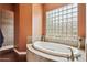 Bright bathroom featuring a soaking tub, glass block window, and tiled shower at 6428 W Eugie Ave, Glendale, AZ 85304