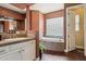 Bathroom featuring a soaking tub, tiled accents, and dual sinks for added convenience at 6428 W Eugie Ave, Glendale, AZ 85304