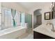 Bright bathroom with a bathtub, a walk-in shower, and double sinks by a window at 719 W Milada Dr, Phoenix, AZ 85041