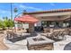 Inviting backyard patio with a fire pit, lounge chairs, and an outdoor kitchen beneath a covered veranda at 7510 E Larkspur Dr, Scottsdale, AZ 85260