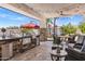 Outdoor kitchen complete with a stone facade, grill, bar seating, and comfortable patio furniture at 7510 E Larkspur Dr, Scottsdale, AZ 85260