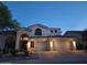 Stunning two-story home featuring arched windows and a three-car garage, illuminated by warm exterior lighting at 7527 E Nestling Way, Scottsdale, AZ 85255
