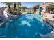 Sparkling pool features a rock waterfall and a waterslide and lush palm trees at 7527 E Nestling Way, Scottsdale, AZ 85255