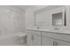 Bathroom with double vanity sinks, white cabinetry, and tub shower with elegant marble backsplash at 8000 W Griswold Rd, Peoria, AZ 85345