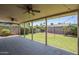 Covered patio with ceiling fans overlooking a spacious backyard with lush green grass and mature trees at 8713 E Sage Dr, Scottsdale, AZ 85250