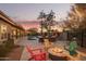 Expansive backyard at dusk showcasing a pool, barbecue area, and a fire pit area with lounge seating at 9432 E Quail Trl, Carefree, AZ 85377