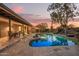Beautiful backyard at sunset featuring a sparkling pool, covered patio, and desert landscaping at 9432 E Quail Trl, Carefree, AZ 85377