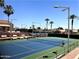 Well-maintained tennis court with lighting and seating amidst palm trees at 10102 E Michigan Ave, Sun Lakes, AZ 85248