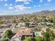 An aerial view captures a desert neighborhood featuring sparkling pools and well-maintained landscaping near mountainous terrain at 10205 E Corrine Dr, Scottsdale, AZ 85260