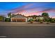 Exterior dusk shot featuring a well-manicured lawn, three-car garage, and tile roof at 10205 E Corrine Dr, Scottsdale, AZ 85260