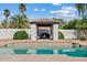 Sparkling in-ground pool with cabana set against a backdrop of palm trees and blue sky at 10205 E Corrine Dr, Scottsdale, AZ 85260