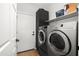 Well-lit laundry room featuring modern front load washer and dryer with gray cabinets and a white paneled door at 10607 E Hillside Mine Ct, Gold Canyon, AZ 85118